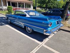 an old blue car parked in a parking lot