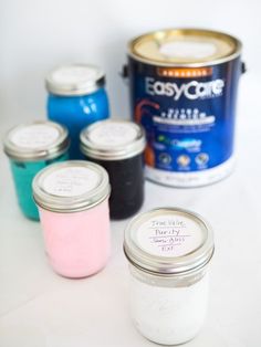 four jars of paint sitting next to each other on a white table with a can of easy care