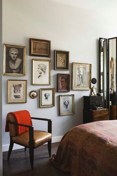 a bed room with a neatly made bed and lots of framed pictures on the wall