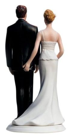 a bride and groom figurine standing next to each other on a white background