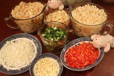 several bowls filled with food on top of a wooden table next to two stuffed animals