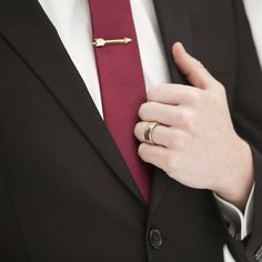 a person wearing a suit and tie with a gold ring on his lapel pin