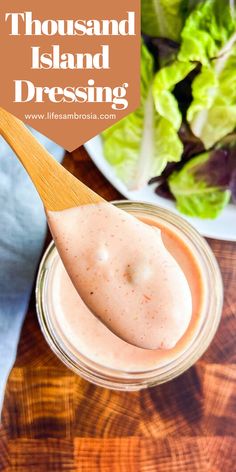 a spoon full of dressing sitting on top of a wooden cutting board next to lettuce