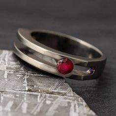 A ruby engagement ring for that unique lady who has her own sense of style and fashion. The clean tension setting hosts this round July birthstone, letting it shine on it's own. RING LAYOUT Ring Width: 5 mm Ring Sleeve: Titanium Ring Profile: Tension Ring Finish: Polished5 mm Titanium - Channel Cut with Tension Stone: Ruby (Qty: 1) Shape/Size: Round, 4 mm Type/Quality: Genuine, AAThis ring has a standard fit.RING FITTING:We highly recommend that you get your ring size in a STANDARD FIT measured Luxury Ruby Ring With Tension Setting As Gift, Ruby Promise Ring With Tension Setting, Fine Jewelry Ruby Ring With Tension Setting For Anniversary, Classic Round Ruby Ring With Tension Setting, Ruby Tension Ring, Tension Ring, Tension Setting, Engraving Fonts, Let It Shine