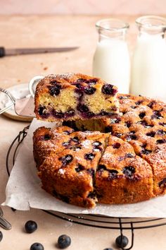 blueberry coffee cake on a wire rack with two glasses of milk in the background