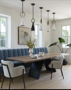 a dining room table surrounded by blue upholstered chairs and white vase with flowers on it