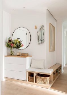 a room with a bench, mirror and vase on the wall next to drawers in front of it