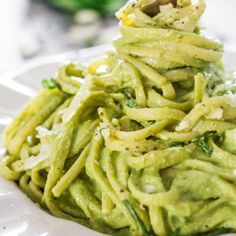 a white plate topped with pasta covered in green sauce