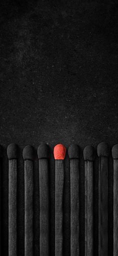 an apple sitting on top of a row of wooden poles in front of a black wall