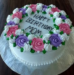 a birthday cake decorated with flowers and the words happy birthday mom on it's frosting