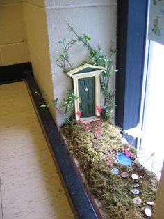 a miniature house in the middle of a window sill with moss growing on it