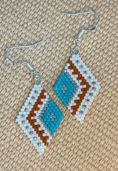 a pair of earrings made out of bead and glass beads sitting on top of a carpet