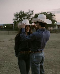 a man and woman wearing cowboy hats in a field