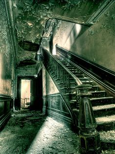 an old staircase leading up to the second floor in a run down building with peeling paint