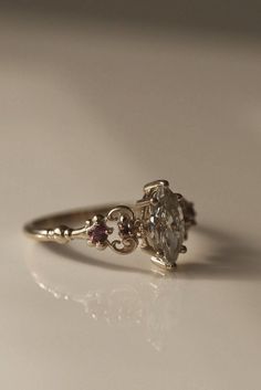 a close up of a diamond ring on a white surface with light shining in the background