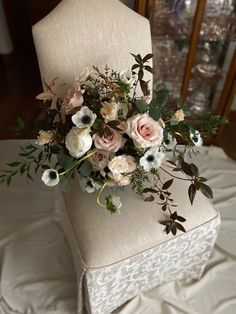 a bouquet of flowers sitting on top of a chair with white and pink flowers in it