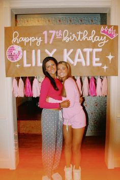 two women standing in front of a sign that says happy 17th birthday lily kate