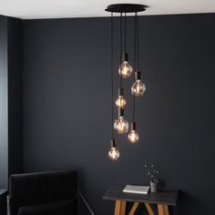 a modern light fixture hanging from the ceiling over a table in a room with dark walls