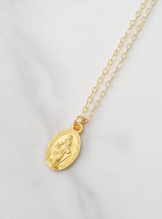 "Sweet Our Lady pendant necklace which is gold plated.  Perfect little gift for Holy Communion. The pendant measures 13mm x 8mm and hangs on a fine gold plated chain. Necklaces where possible will arrive on a necklace card and placed inside an organza bag ready for giving - see last picture. This item ships from the UK within 1 working day. PLEASE NOTE gold and silver plated items should not be worn in the shower, bath or the pool. Chemicals such as lotions or perfumes will \"damage\" the metal Gold Miraculous Medal Necklace Gift, Gold Oval Charm Necklace With Adjustable Chain, Personalized Oval Gold Necklaces, Personalized Gold Oval Necklace, Personalized Oval Gold Necklace, Gold Round Pendant With Miraculous Medal, Gold-plated Jewelry With Miraculous Medal, Gold Miraculous Medal Round Pendant Jewelry, Gold Oval Pendant Locket Necklace Gift