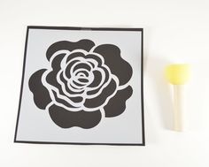 a black and white flower cut out next to a yellow lollipop on a white background