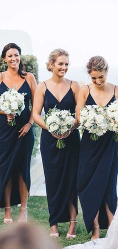 the bridesmaids are all wearing navy blue dresses and holding bouquets in their hands