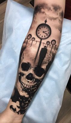 a person with a clock and skull tattoo on their arm