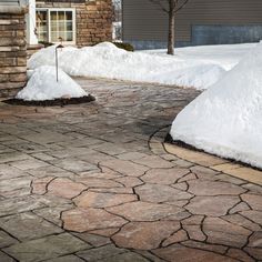 a driveway with snow on the ground and trees in the background