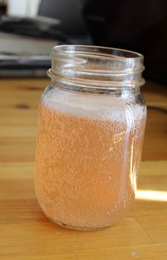 a jar filled with liquid sitting on top of a wooden table