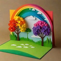 an open card with trees and rainbows on the front, sitting on a table