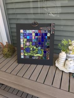 an art piece is displayed on a wooden table next to potted plants and vases