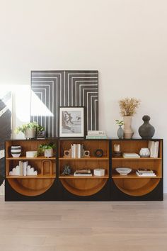 a living room with an entertainment center and vases on top of the shelves in front of it