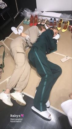 two people laying on the ground with shoes in front of them and one person wearing green pants