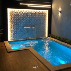 an indoor swimming pool with blue water and lights on the wall behind it, surrounded by wood flooring