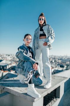 two young women standing on top of a building