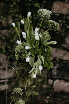 a vase filled with white flowers and greenery