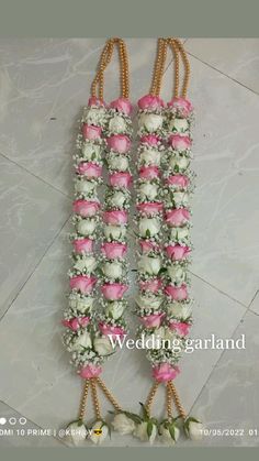 wedding garlands with pink and white flowers hanging from the side on marble flooring