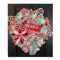 a christmas wreath with candy canes and merry lettering on the front door to welcome you