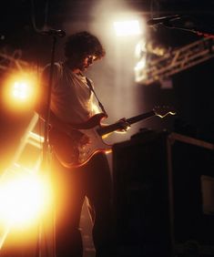 a man playing guitar on stage with lights behind him