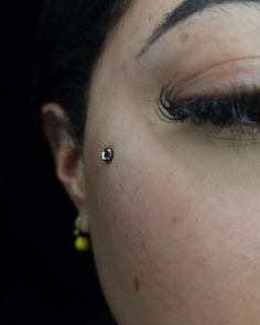 a close up of a woman's face with piercings on her nose and eyes