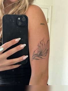 a woman is holding her phone up to the camera with a flower tattoo on it