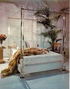 a white bed sitting next to a tall plant in a living room filled with furniture