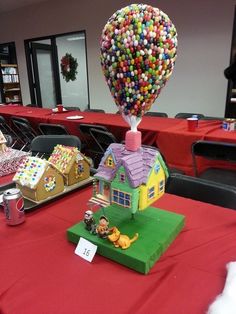 a table topped with lots of candy covered houses and balloons in the shape of houses