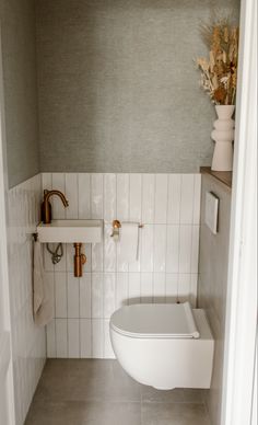 a white toilet sitting in a bathroom next to a wall mounted faucet and sink