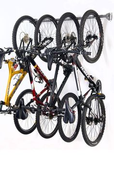 three bikes are hanging on the wall with wheels attached to each bike and one is yellow