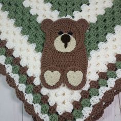 a crocheted teddy bear is laying on top of a blanket that has hearts