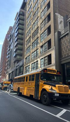 a yellow school bus parked in front of a tall building