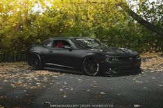 a black sports car parked in front of some trees