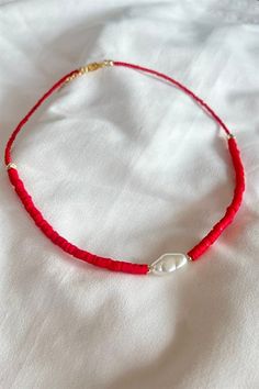 a red string bracelet with a white pearl bead