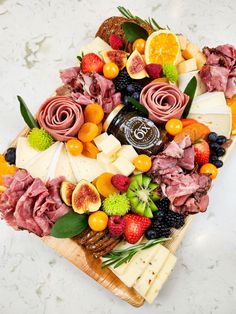 an assortment of cheeses, fruits and meats on a cutting board