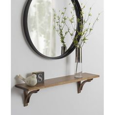 a wooden shelf with a mirror and vase on it next to a wall mounted clock